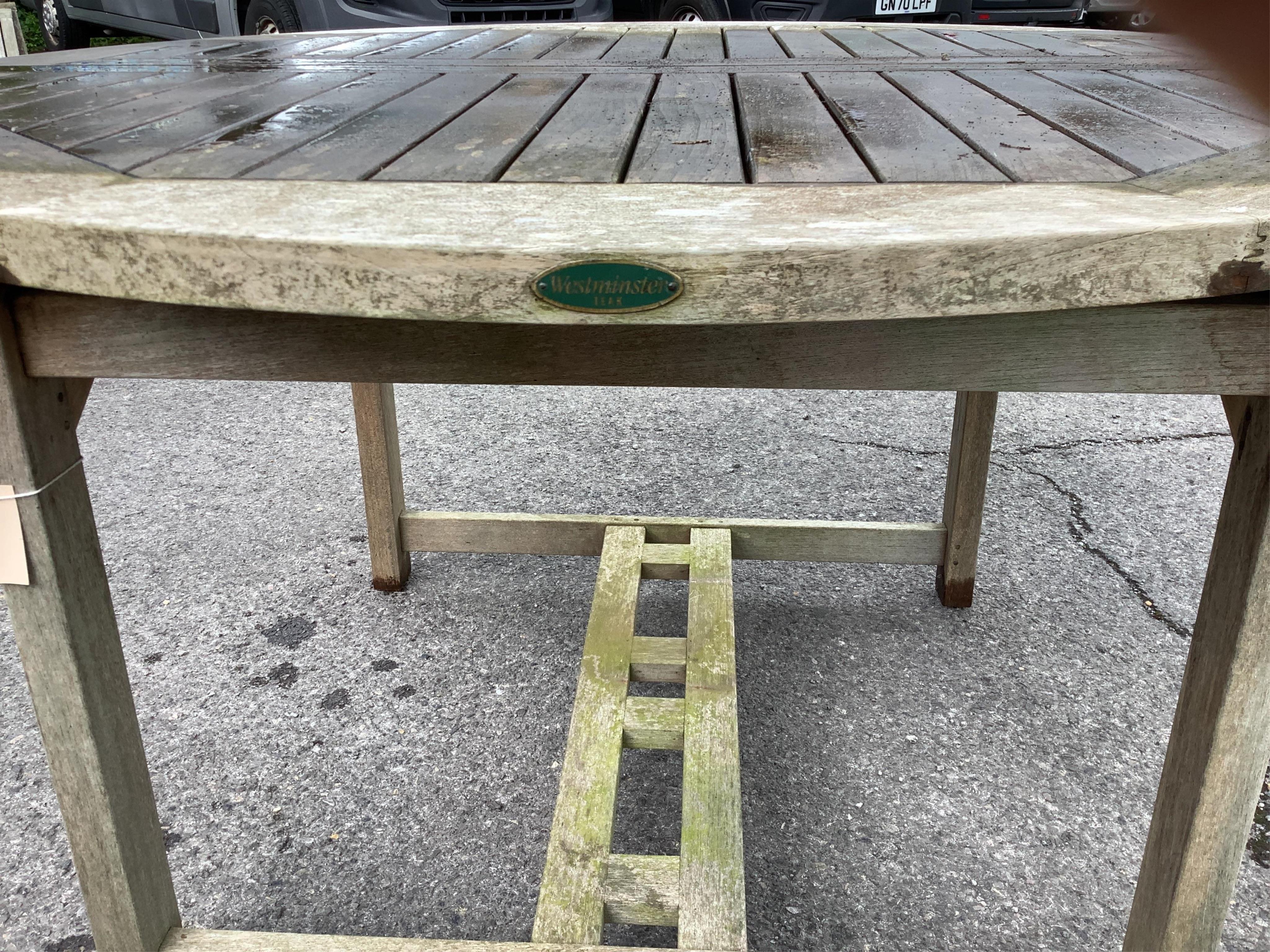 A Westminster circular weathered teak extending garden table, (leaf not functioning correctly), diameter 120cm, height 75cm. Condition - fair